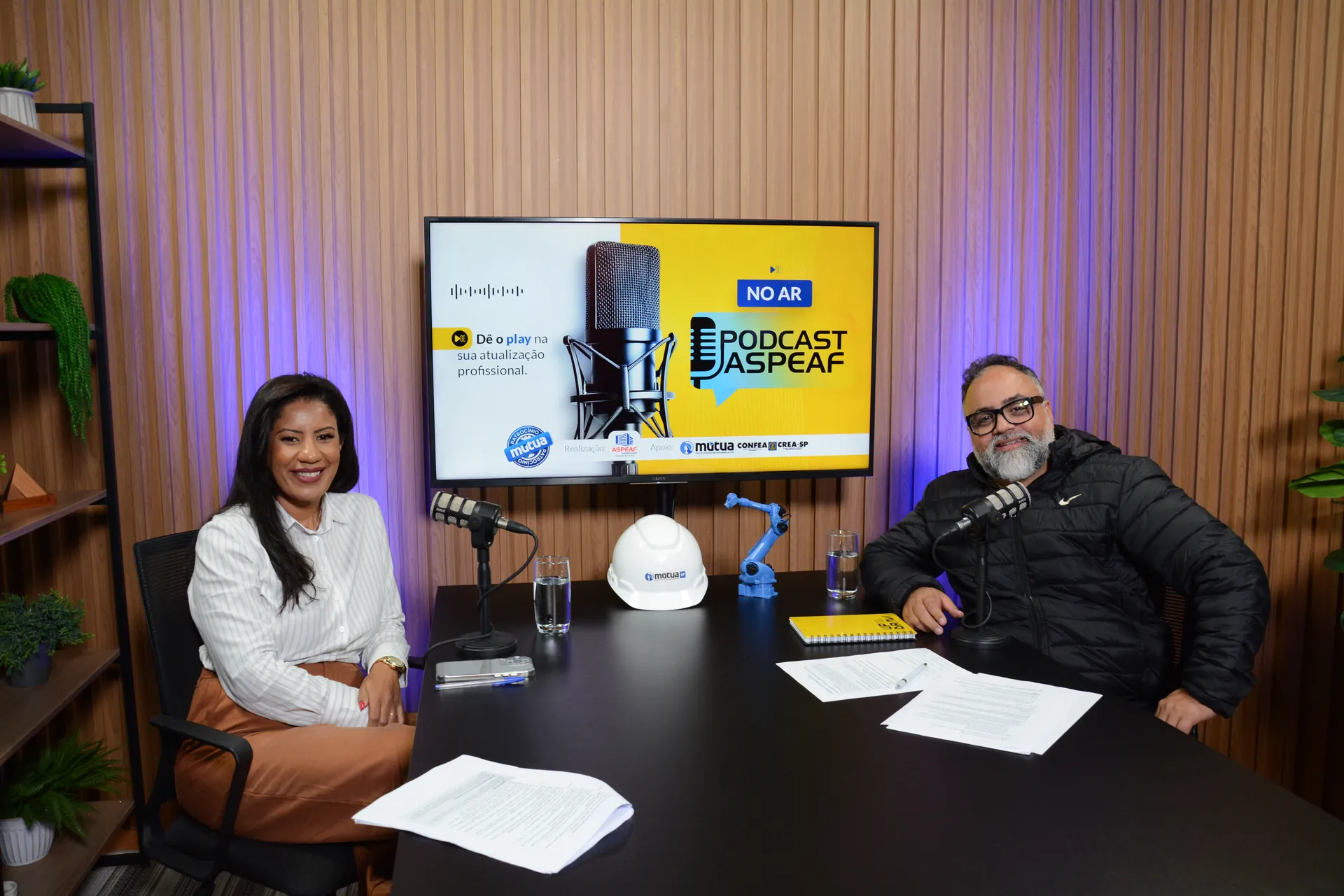 Bancada do podcast com dois convidados e os microfones