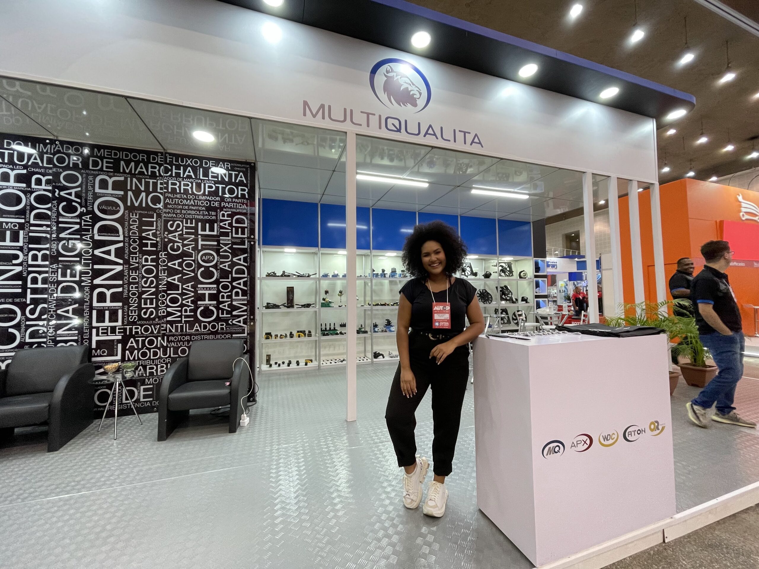 Parede do stand com os nomes das peças em tipografia, e a vitrine de produtos ao fundo