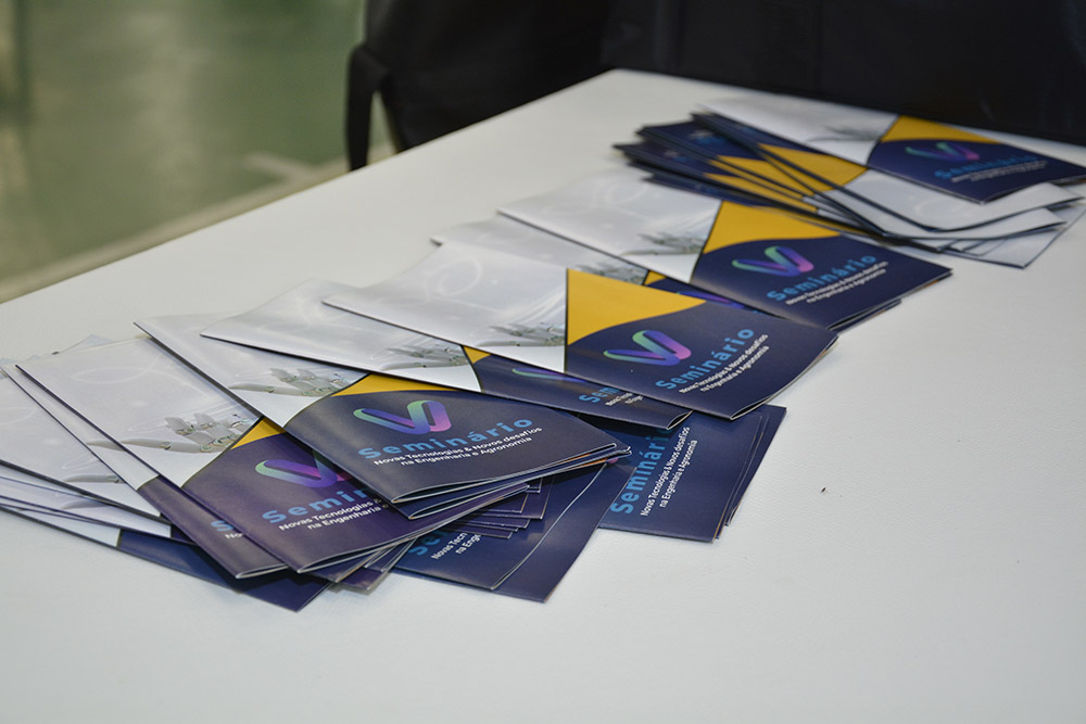 Palestrante no V Seminário, com a identidade do evento ao fundo