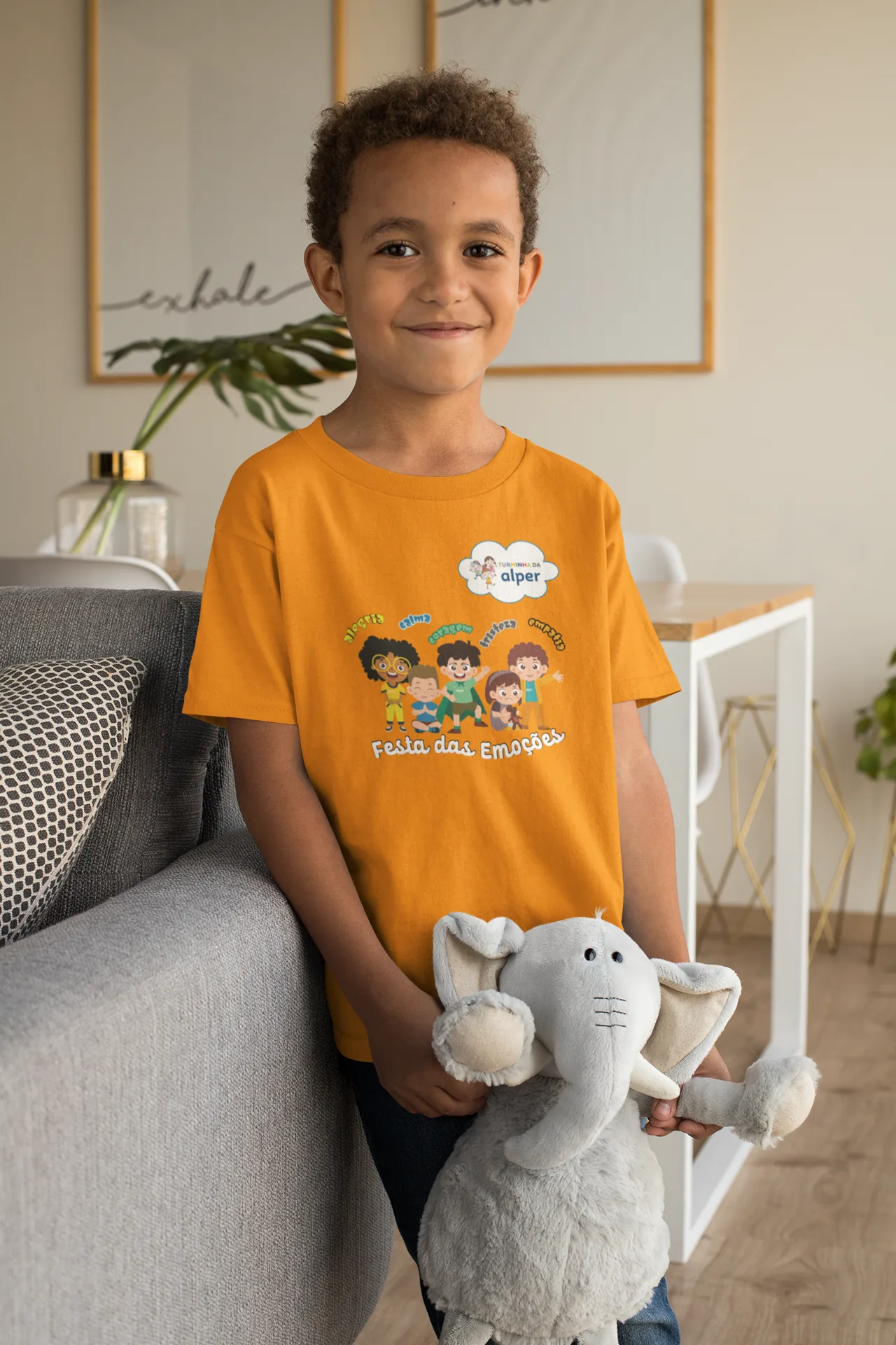 Criança com a camiseta laranja da emoção Empatia, segurando um bicho de pelúcia